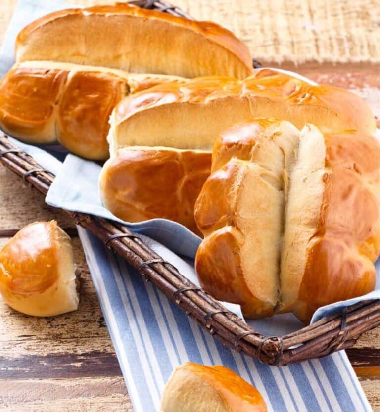 Imagem de um pão sovado caseiro, com textura macia e superfície dourada, servido em uma mesa rústica com um pano de fundo acolhedor.